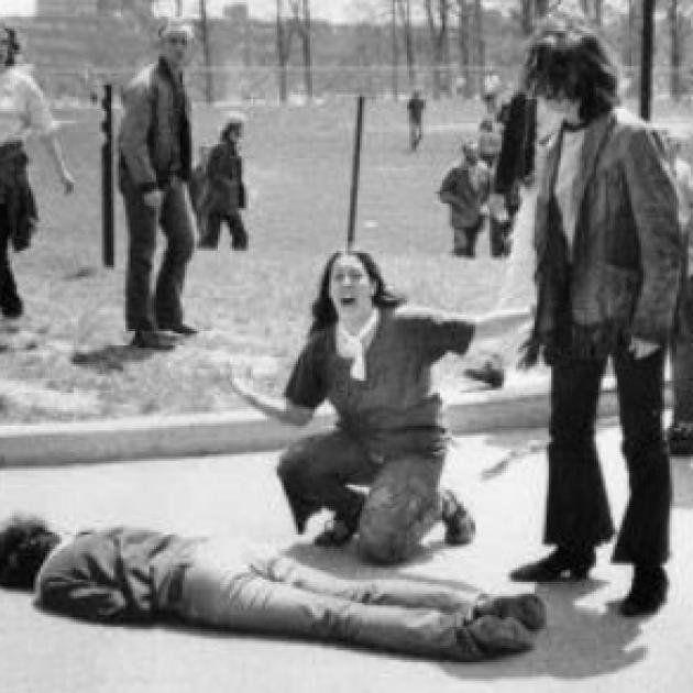 Man lying on the ground dead a woman screaming over his body, others looking on