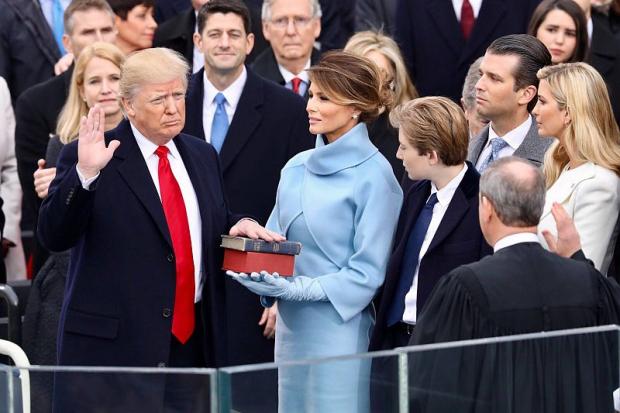 Donald Trump frowning with hand on Bible at swearing in ceremony