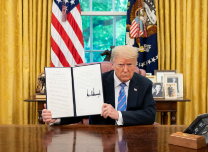 Trump at desk holding up Executive Order