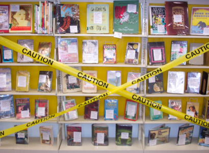 Books on shelves with Caution yellow tape across them