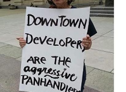 Sign being held outside reading Downtown developers are the aggressive panhandlers