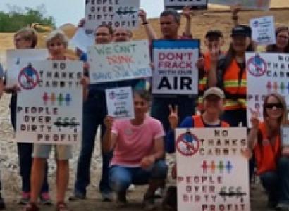 Many people posing outside holding signs about the environment