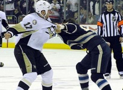 Two hockey players fighting on the ice with a ref looking on