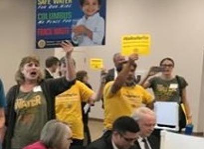 Lots of people holding signs in a room together yelling