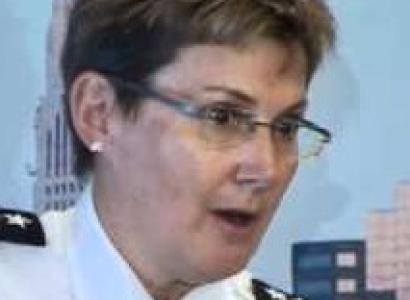 White women with glasses and short brown hair wearing a police uniform looking surprised