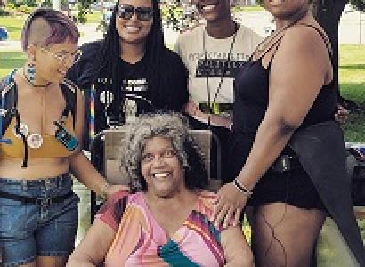 Four young black women posing behind an older black woman in a chair