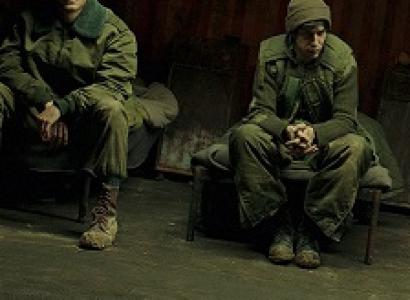 Two young white men in military uniforms sitting dejectedly on a bench