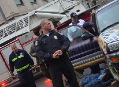 Cops and person lying on ground next to a car with a fire truck