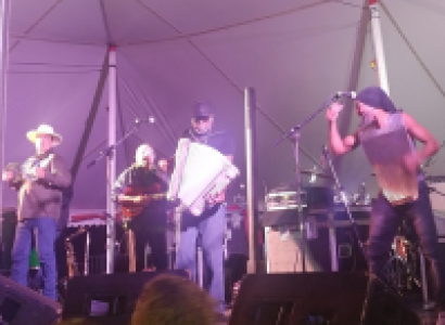 Three musicians on a stage, one playing an accordion