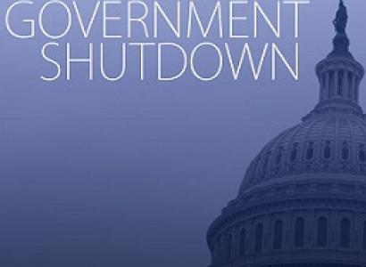 Blue background white letters saying Government Shutdown and the edge of the capitol building in DC