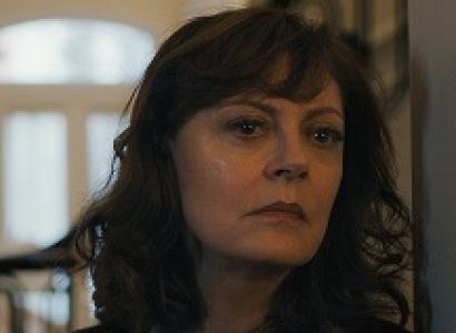 White woman with long curly brown hair looking pensive