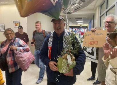 Man walking through airport holding a plant with people and balloons surrounding him