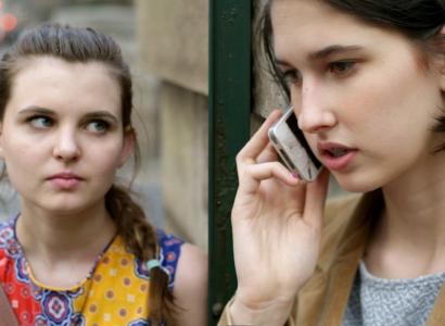 A woman on the phone and another woman looking at her in an alarmed way
