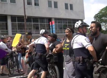 Police al suited up with helmets and bikes attacking stationary black people with black tape over their mouths