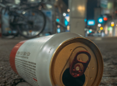 Empty beer can on the ground outside at night