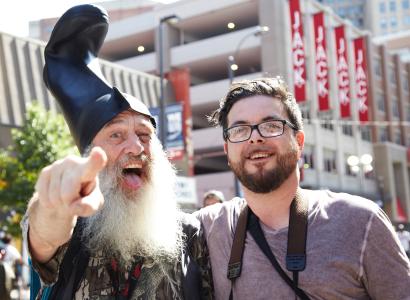 Guy with white beard and funny hat standing next to young man with glasses