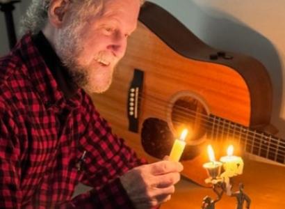 Bill Cohen with candle and guitar