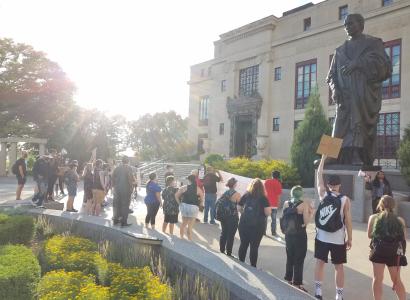 People protesting outside City Hall and large Columbus statue