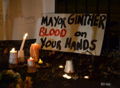 Candles and a sign that says "Mayor Ginther Blood on your hands"