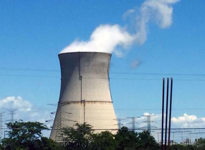 Nuclear tower with lots of white smoke coming out against a blue sky