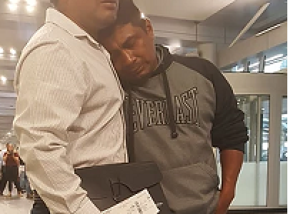 Two Latino men, one hugging the other, looking very sad