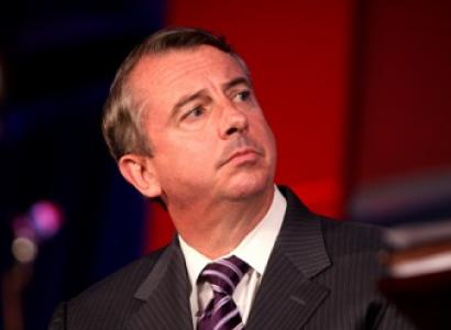 Middle aged white guy with receding brown hair looking sideways with a worried look on his face, wearing a gray suit with a purple and white striped tie