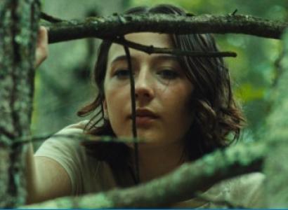 Woman peering through branches of tree