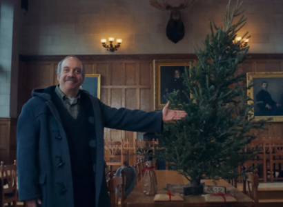 Older white man gesturing toward a decorated Christmas tree