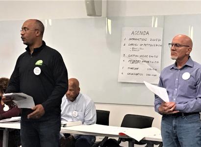 Two men at the front of a room speaking