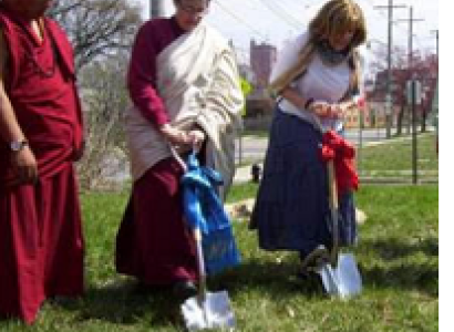 Three people digging into the ground, two wearing Buddhist garb