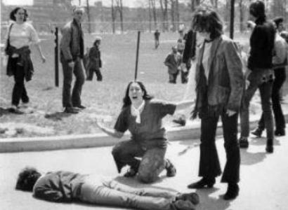 Man lying on the ground dead a woman screaming over his body, others looking on