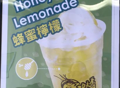 A sign with a cup with yellow liquid and words Kung Fu Tea