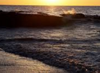 A beach with sun rising and waves coming in 