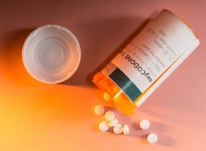 A pill bottle with white pills spilling out