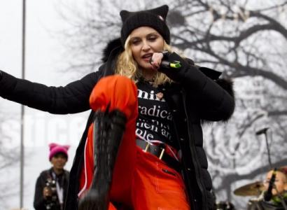 Madonna in orange pants and black bots dancing outside