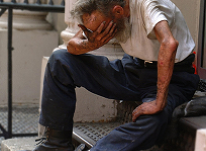 Man with head in hand in despair sitting outside on stairs