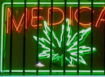 Neon sign glowing in window orange letters saying Medical and Green image of a marijuana leaf