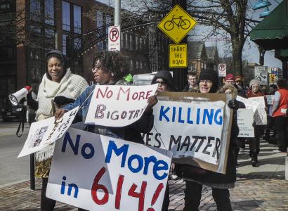 People marching down High Street holding signs that say No More in 614, no more bigotry, black lives matter.
