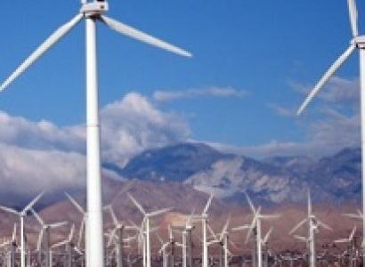 Two large white wind turbines in the foreground and a bunch of them in the distance