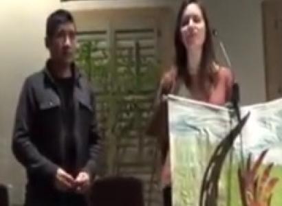 Latino man and white woman standing at front of event speaking