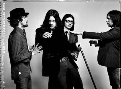 Black and white photo of four white guys in a band with suits on posing like they are moving around funny