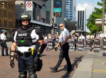 Protestors with shields as police in riot gear prepare for attack