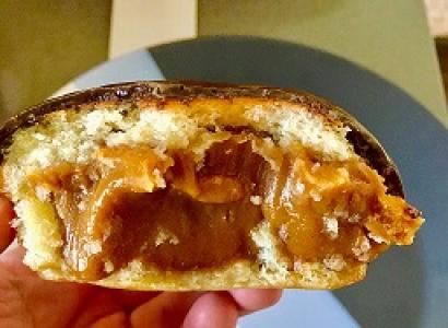 A hand holding a pastry that seems to be filled with yellowish fruit