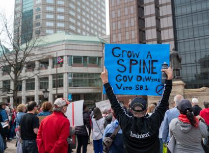 Sign says Grow A Spine Gov Dewine At Protest