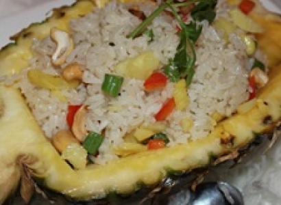 Pineapple cut in half with lots of rice and vegetables inside