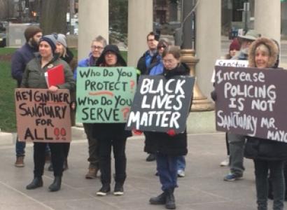 People outside City Hall holding signs 