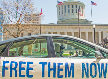 Car with sign saying Free Them Now in front of Ohio Statehouse
