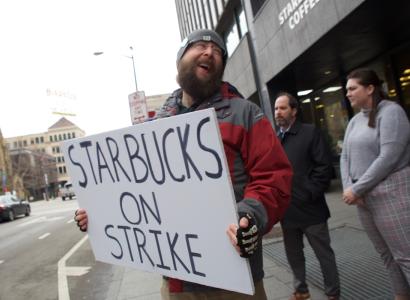 Guy outside Starbucks holding a sign saying Starbucks on strike