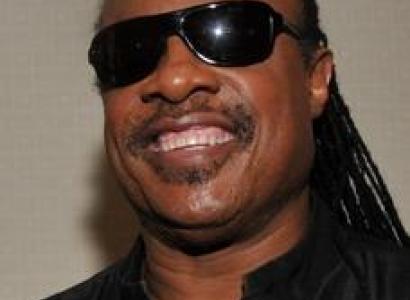 Smiling black man with big sunglasses and long braids in a black shirt