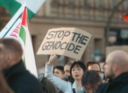 Woman holding sign at rally saying Stop the Genocide